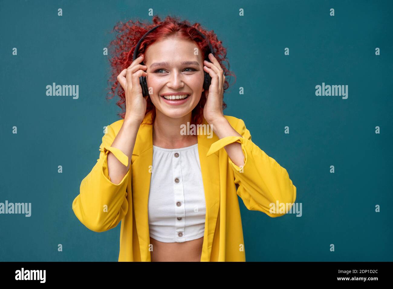 Jeune femme aux cheveux bouclés rouges portant un casque amusant écouter de la musique Banque D'Images Jeune femme aux cheveux bouclés rouges portant un casque amusant écouter de la musique Banque D'Images