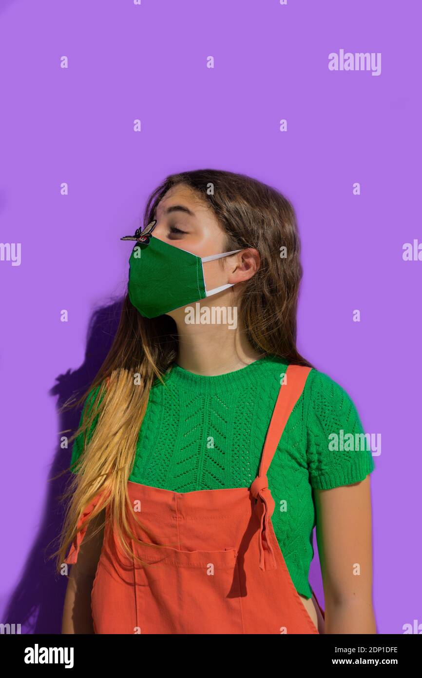 Adolescente portant un masque de protection regardant l'autocollant de mouche sur le nez Banque D'Images