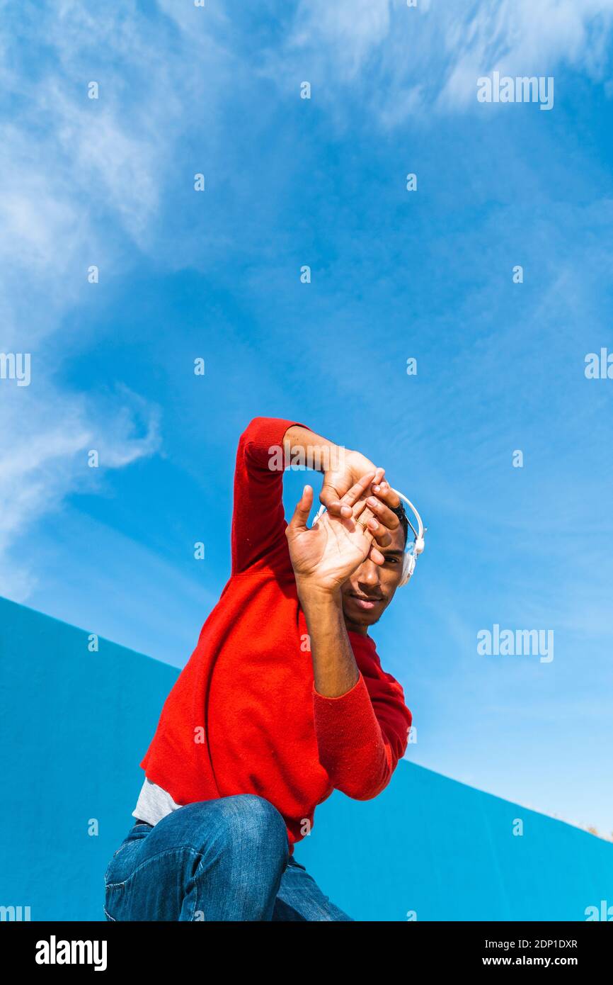 Jeune homme avec des écouteurs, l'écoute de la musique, de la danse sur le mur jaune Banque D'Images