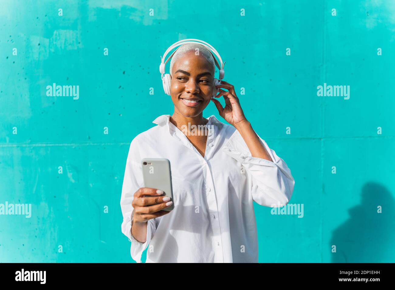 Belle femme debout devant un mur de thé, écoutant de la musique, prenant des selfies Banque D'Images