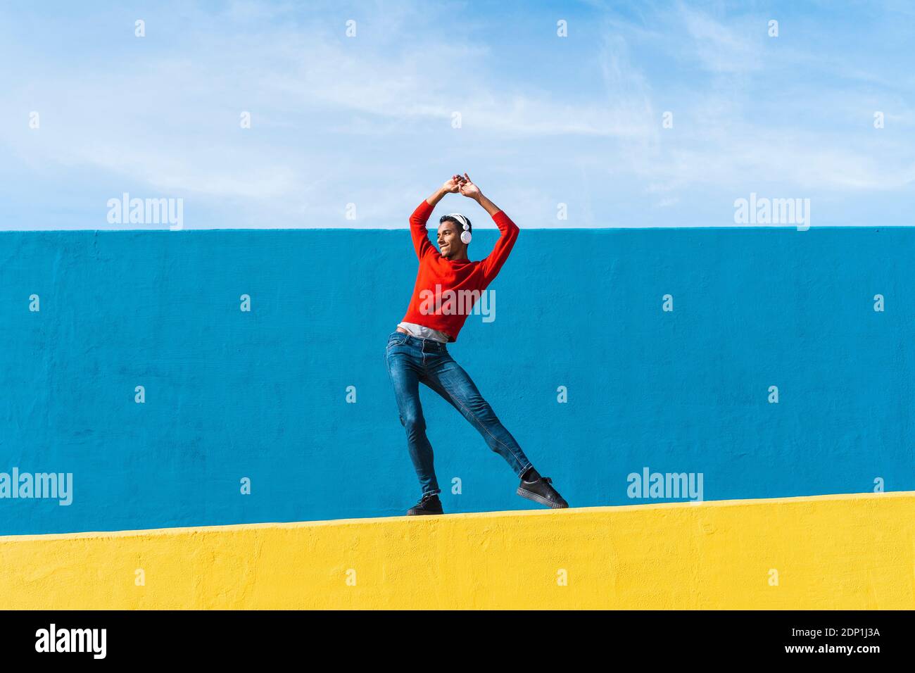 Jeune homme avec des écouteurs, l'écoute de la musique, de la danse sur le mur jaune Banque D'Images