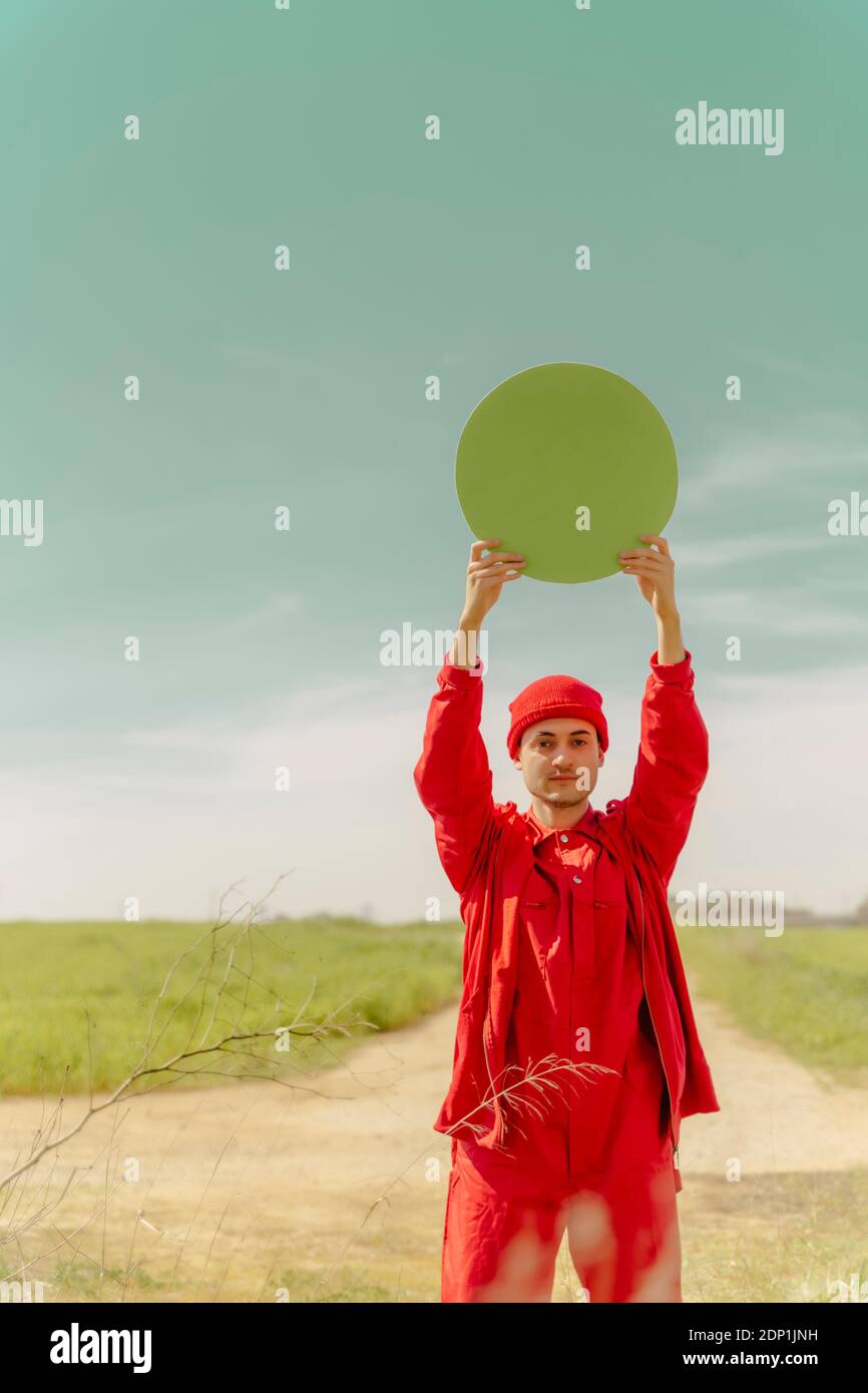 Portrait d'un jeune homme vêtu de rouge tenant un cercle vert Banque D'Images