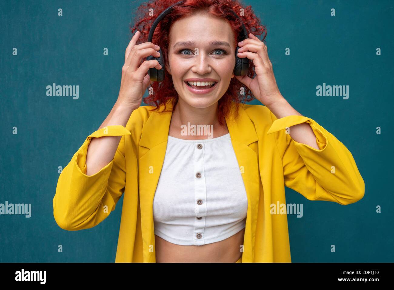 Jeune femme aux cheveux bouclés rouges portant un casque amusant écouter de la musique Banque D'Images Jeune femme aux cheveux bouclés rouges portant un casque amusant écouter de la musique Banque D'Images