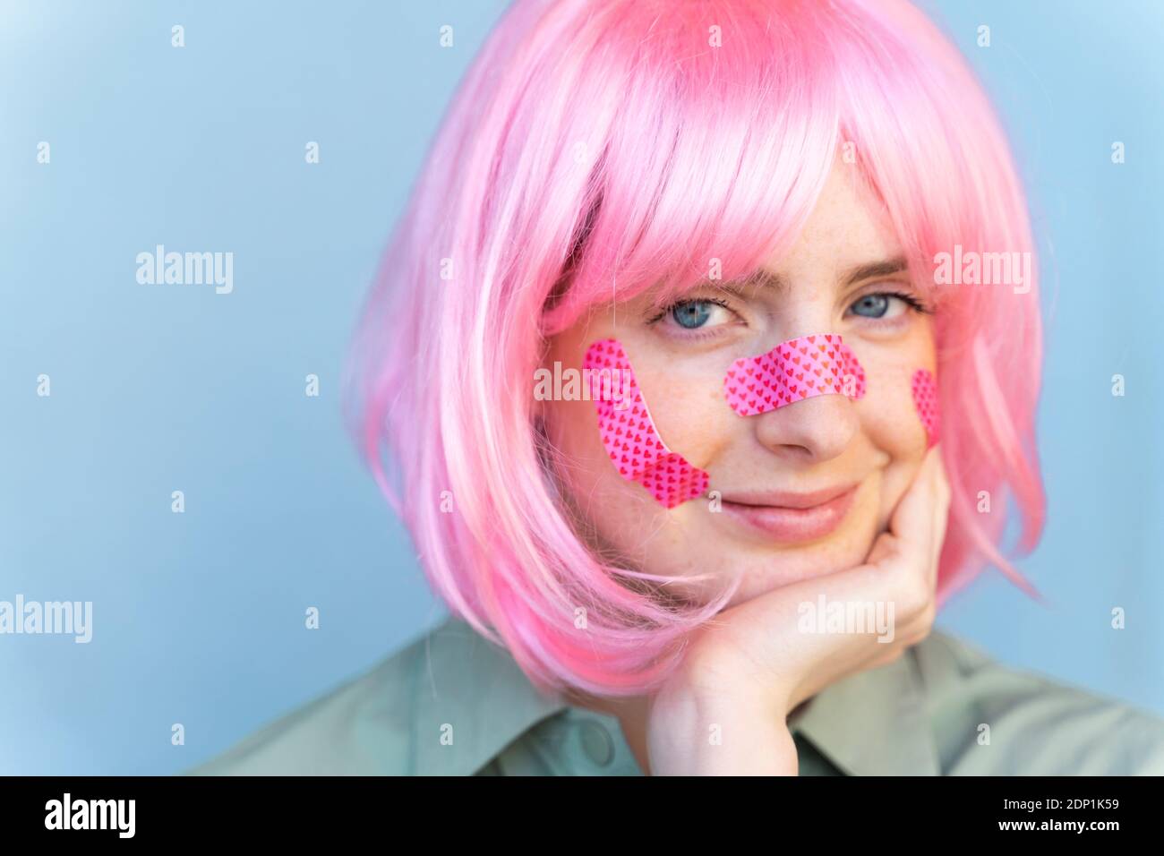 Portrait d'une jeune femme portant une perruque rose avec des pansements son visage Banque D'Images