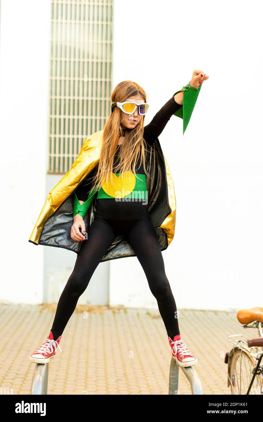 Jeune fille en costume super héroïne sur support à bicyclettes Banque D'Images