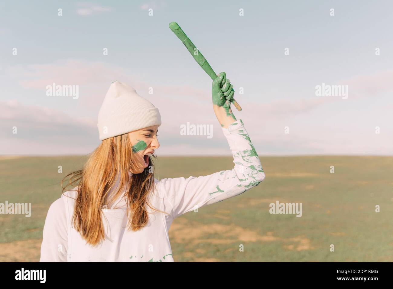 Femme hurlant tenant un bâton peint vert Banque D'Images