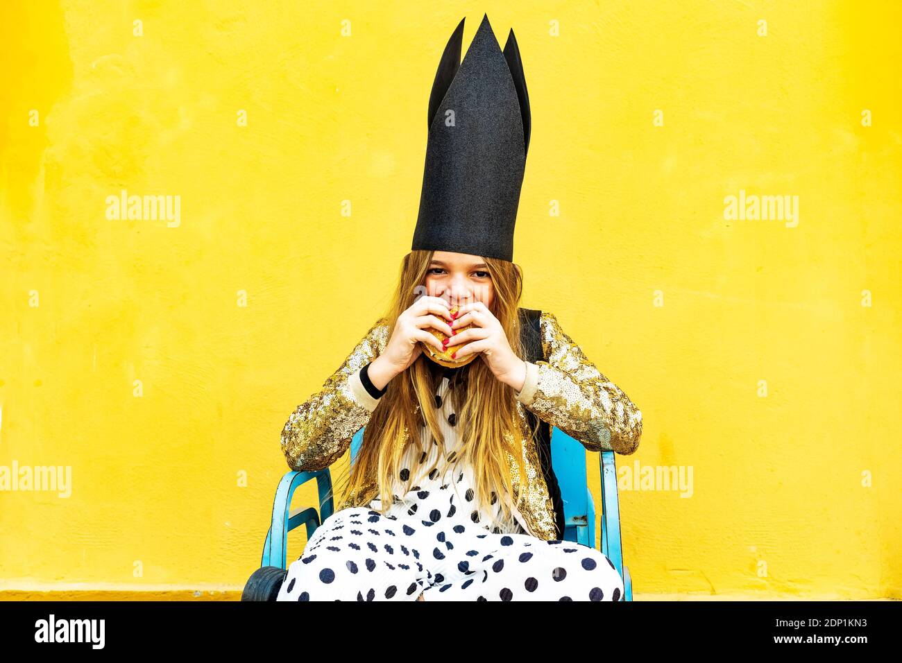 Portrait of Girl wearing black crown eating Hamburger Banque D'Images