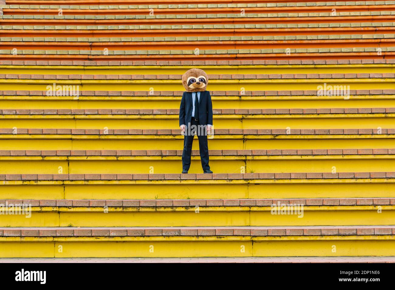 Homme d'affaires en costume noir avec masque de meerkat debout sur les escaliers Banque D'Images