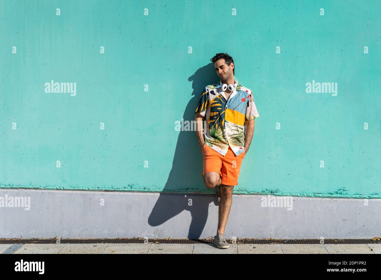Homme froid debout devant le mur vert avec les mains dans les poches Banque D'Images