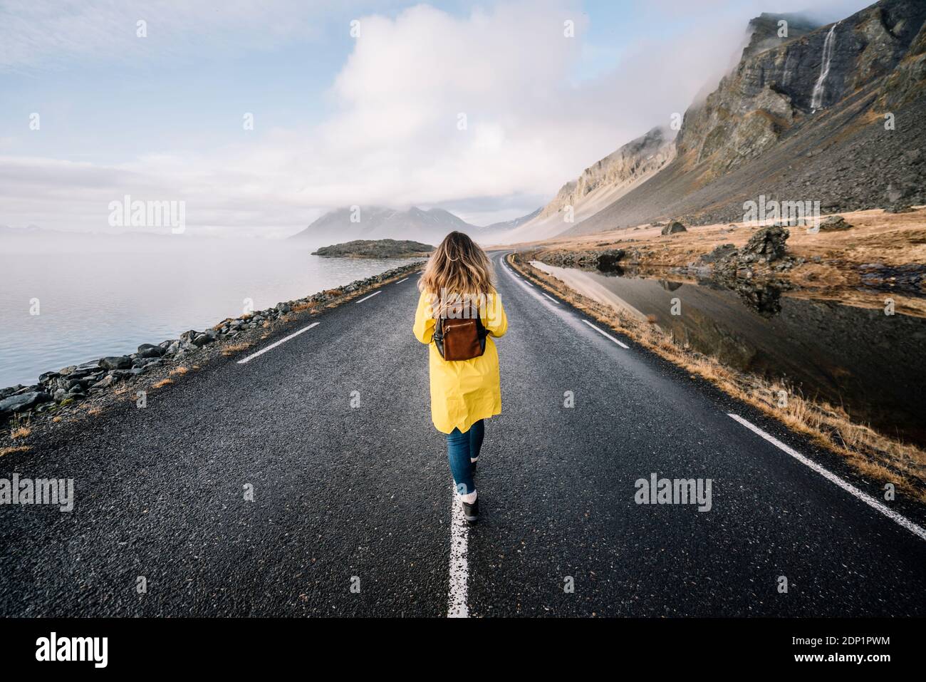 Vue arrière de l'Islande, avec sac à dos femme marche sur bande médiane de country road Banque D'Images