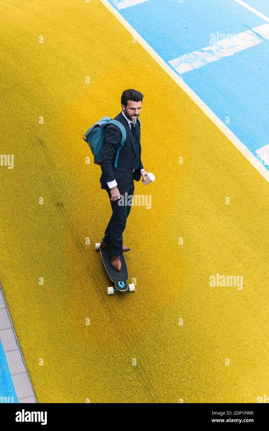 Jeune homme d'affaires skate dans une rue jaune et bleue Banque D'Images