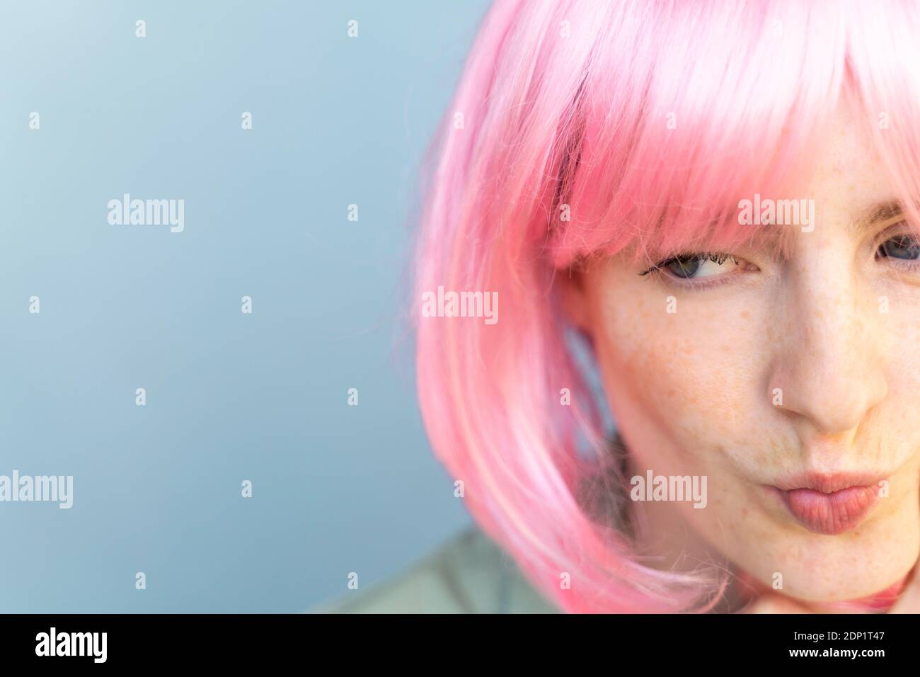 Portrait d'une jeune femme portant une perruque rose qui lui fait moucher la bouche Banque D'Images