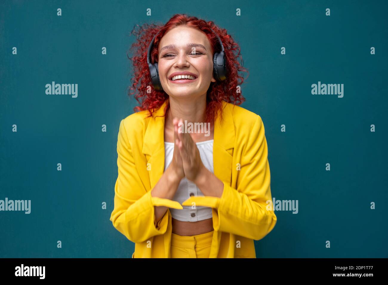 Jeune femme aux cheveux bouclés rouges portant un casque amusant écouter de la musique Banque D'Images Jeune femme aux cheveux bouclés rouges portant un casque amusant écouter de la musique Banque D'Images