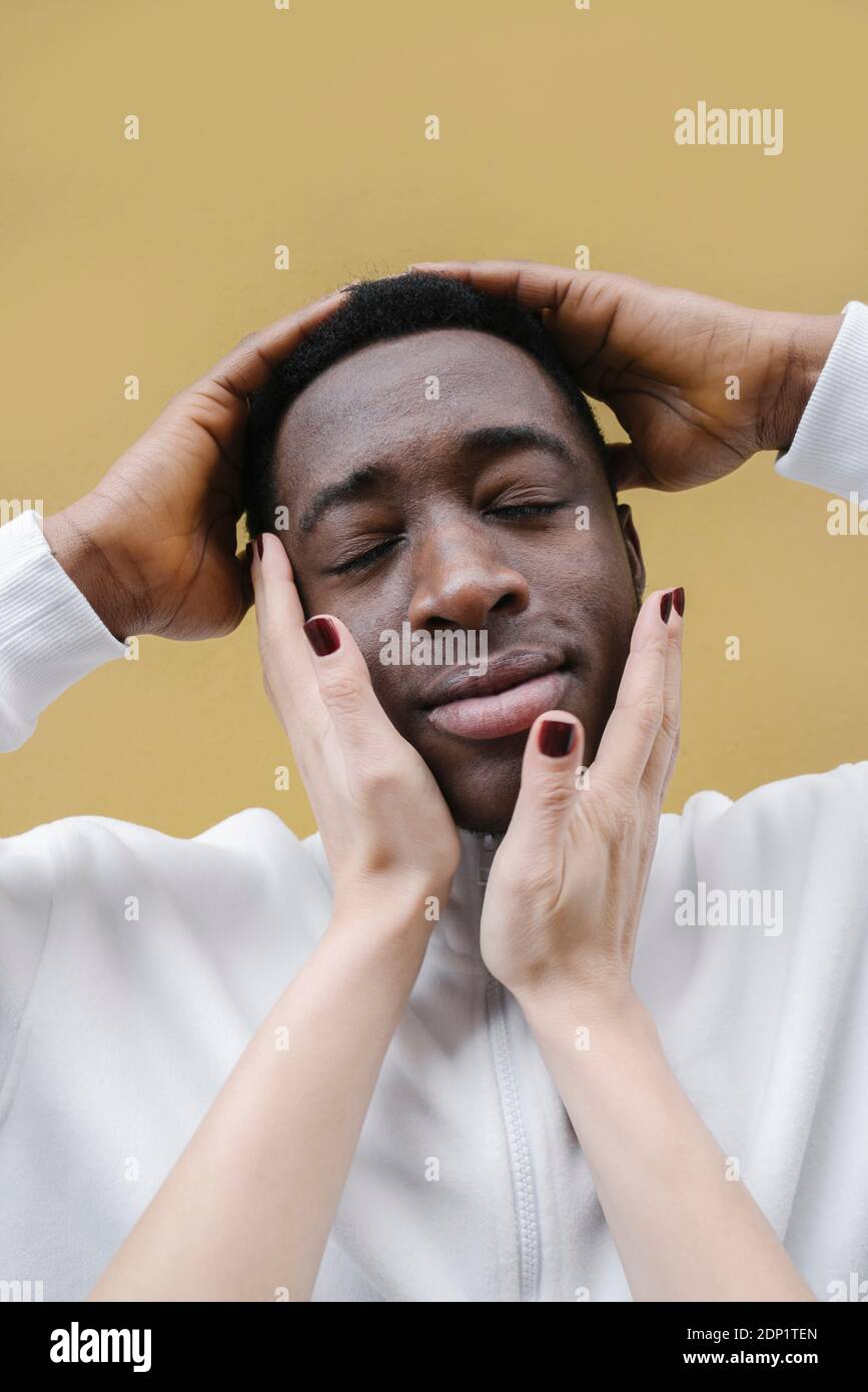 Portrait d'un jeune homme détendu touché par les mains de la femme Banque D'Images