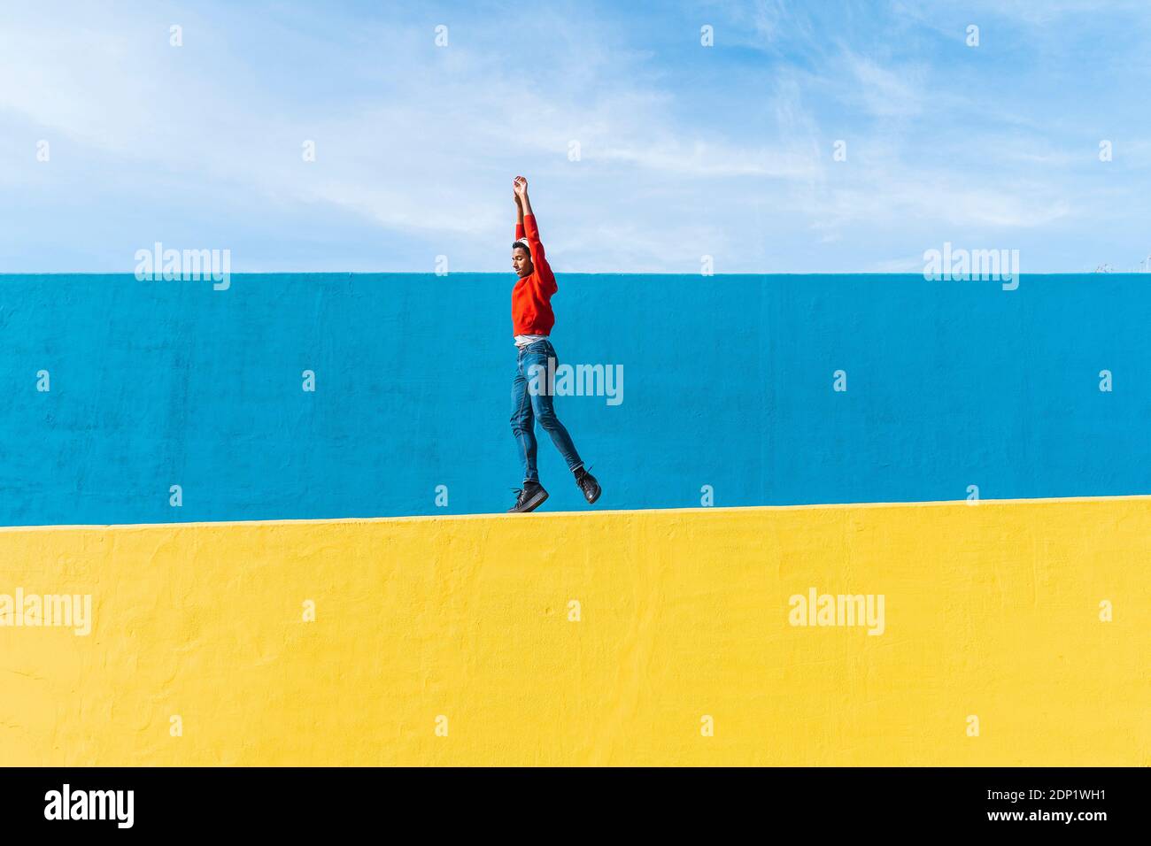 Jeune homme avec des écouteurs, l'écoute de la musique, de la danse sur le mur jaune Banque D'Images
