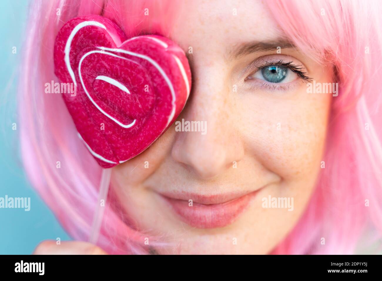 Portrait d'une jeune femme portant un perruque rose avec une couverture en forme de coeur son œil Banque D'Images