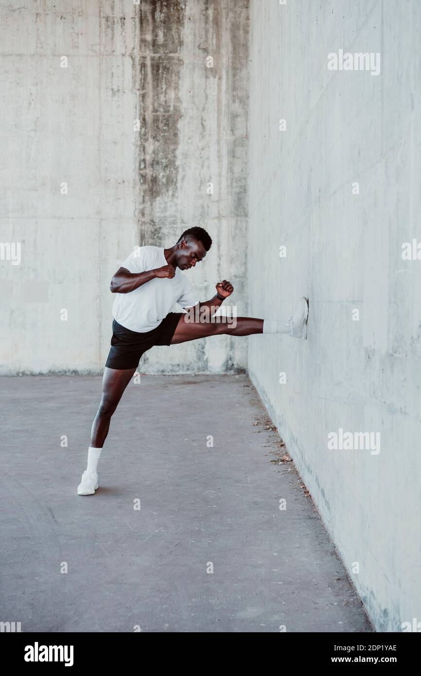 Male athlete exercising by white wall Banque D'Images