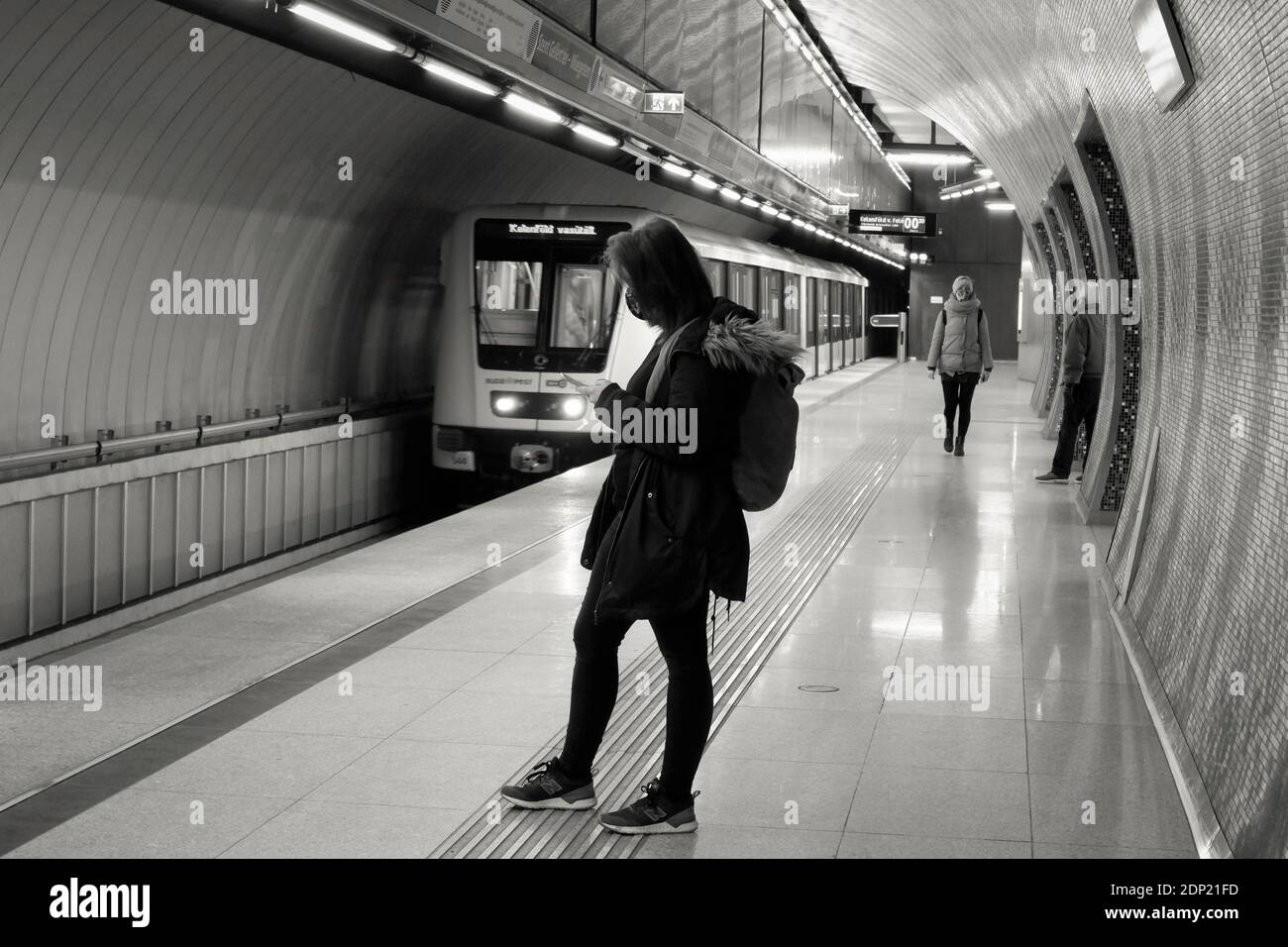 Budapest, Hongrie - 18 décembre 2020 : jeune femme en masque attendant le métro en couleurs monochromes Banque D'Images