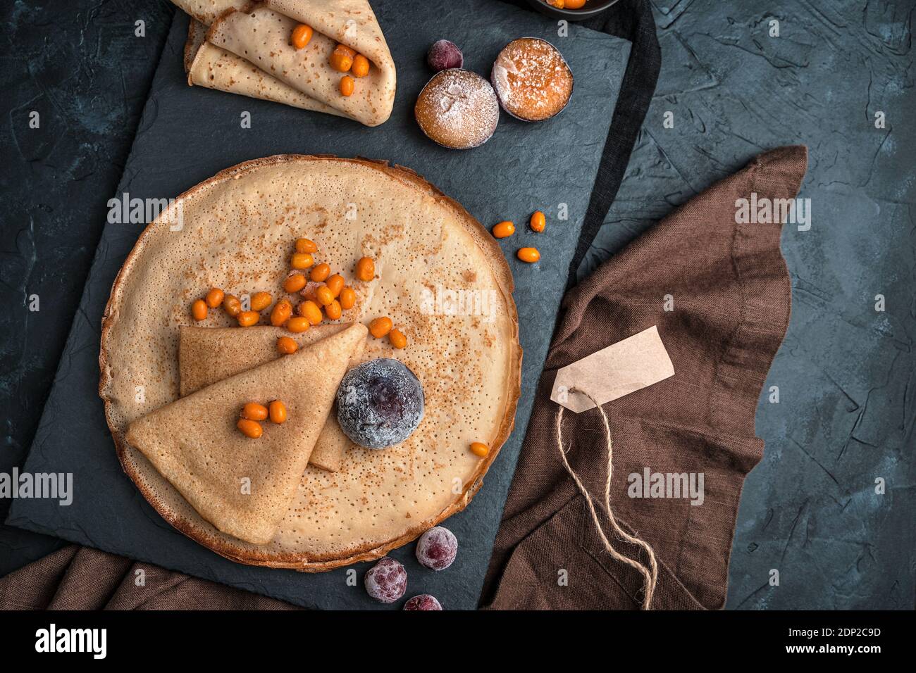 Busthorn de mer surgelé, cerise, prune sur des crêpes sur fond noir. Banque D'Images