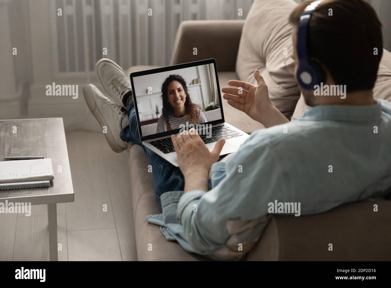 Homme millénaire calme se détendant sur le canapé discutant avec la femme en ligne Banque D'Images