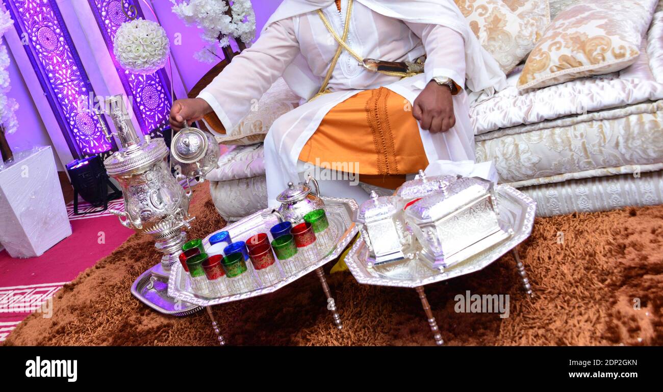 Homme marocain en robe traditionnelle. Égouttez le thé dans des tasses colorées. Thé marocain à la menthe. Banque D'Images