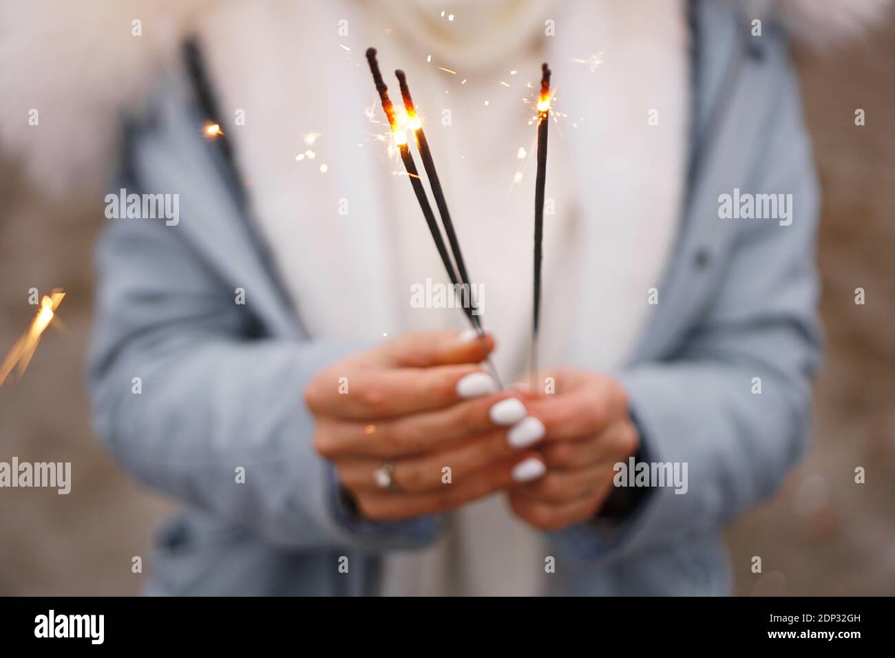 Les mains des femmes tiennent des étincelles en feu. Femme à l'extérieur en hiver Banque D'Images