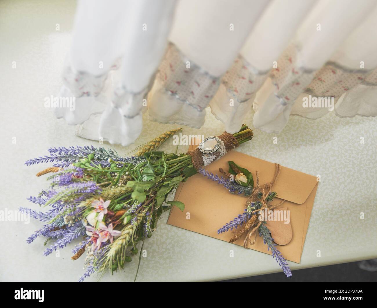 un bouquet de lavande de style boho se trouve sur la fenêtre près de l'enveloppe faite à la main, sur la robe de mariage Banque D'Images