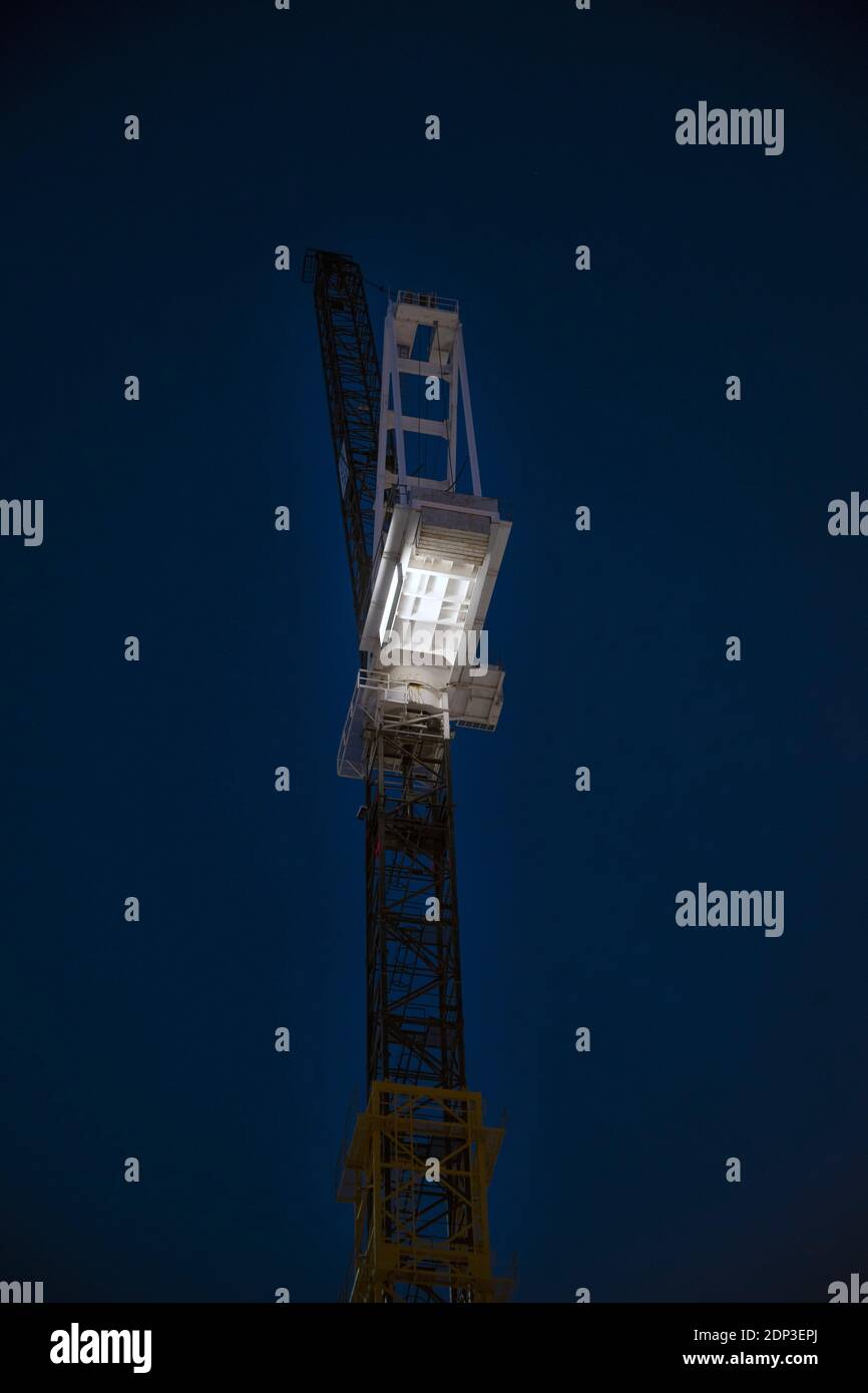 Grue de tour la nuit, illuminée contre le ciel de nuit Banque D'Images