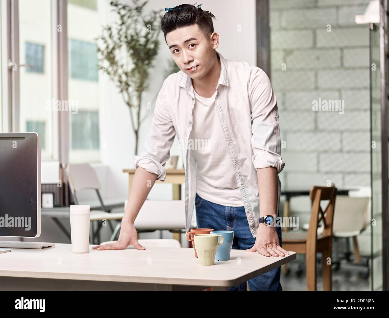 portrait d'un jeune entrepreneur asiatique debout à la recherche d'un bureau à l'appareil photo Banque D'Images