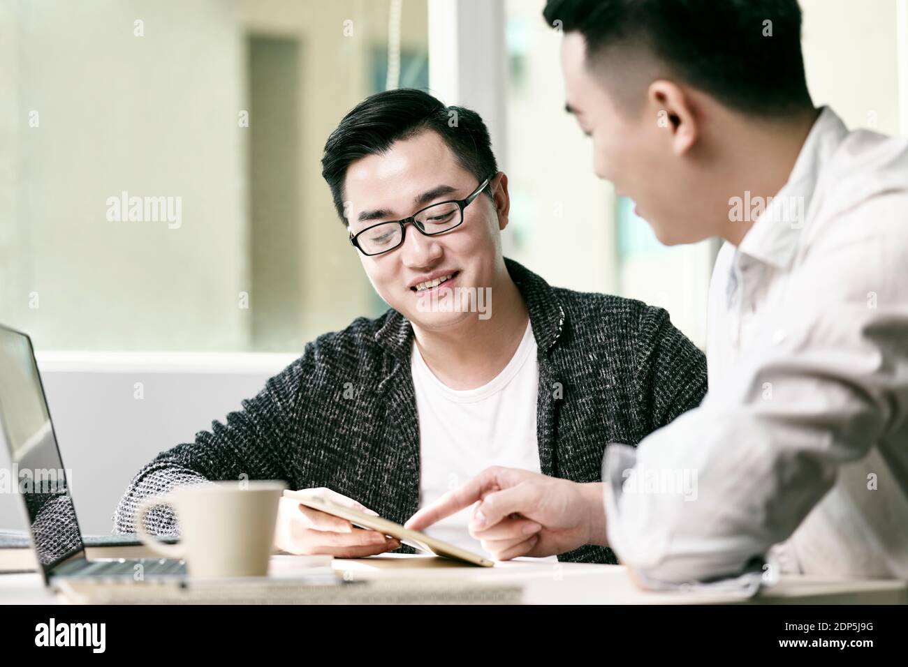deux jeunes entrepreneurs asiatiques discutant des affaires au bureau en utilisant le numérique tablette et ordinateur portable Banque D'Images