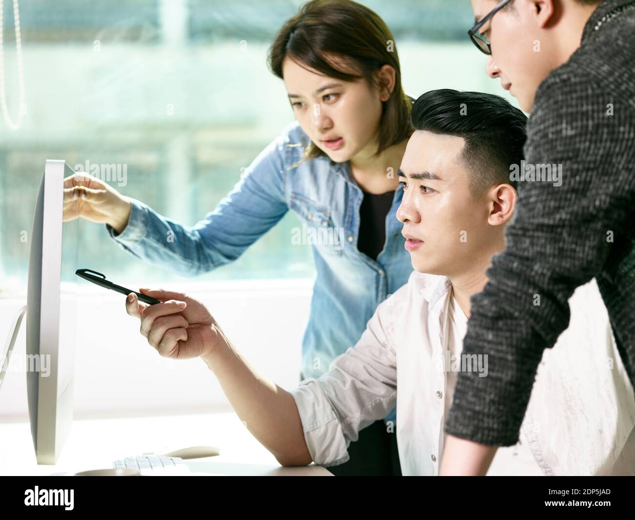 une équipe de jeunes asiatiques discutant des affaires au bureau avec ordinateur de bureau Banque D'Images
