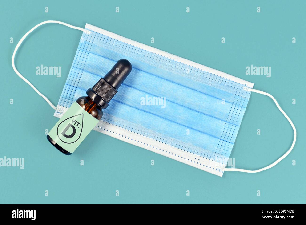 La vitamine D aide à lutter contre la maladie du virus Corona. Concept avec masque médical et flacon avec gouttes de vitamine sur fond bleu Banque D'Images