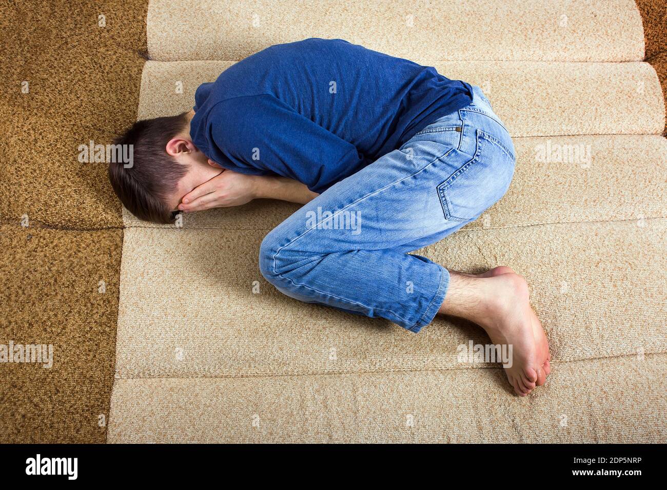 Triste jeune homme cacher un visage sur le canapé Banque D'Images