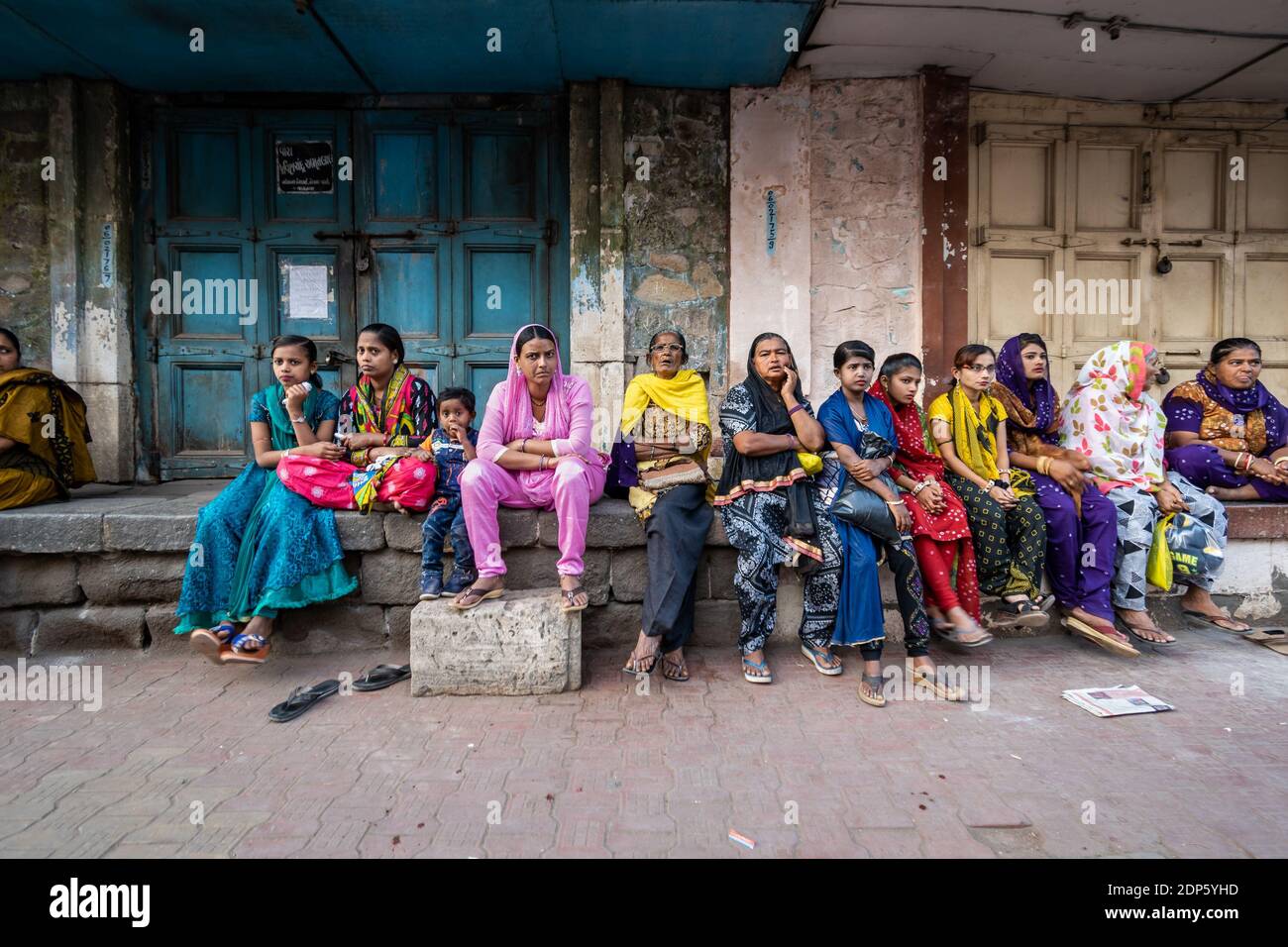 Jamnagar, Gujarat, Inde - décembre 2018 : un grand groupe de femmes indiennes portant des vêtements colorés assis sur un porche en bord de route dans les rues du Cit Banque D'Images