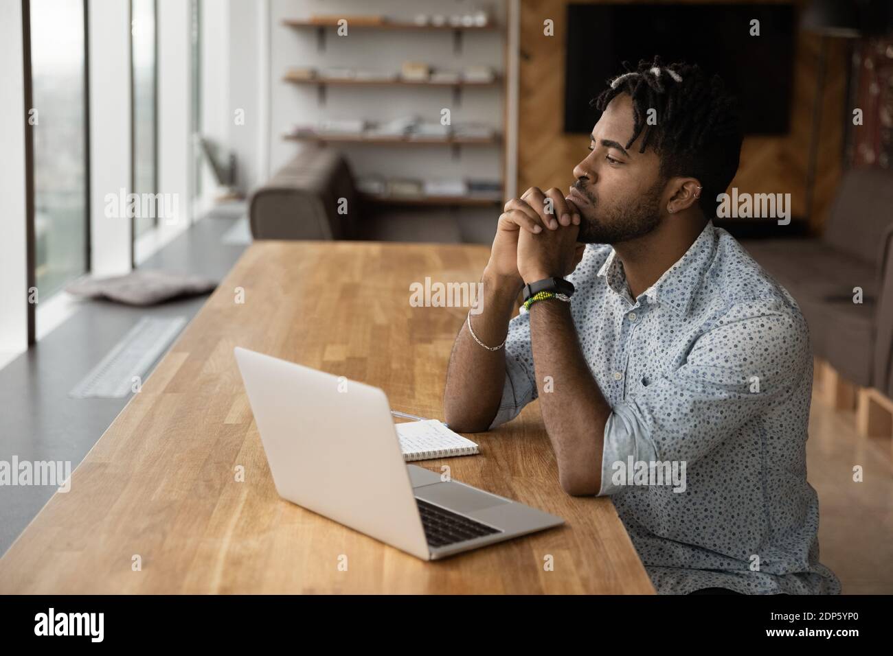Un homme biracial pensif travaille sur la pensée d'un ordinateur portable Banque D'Images