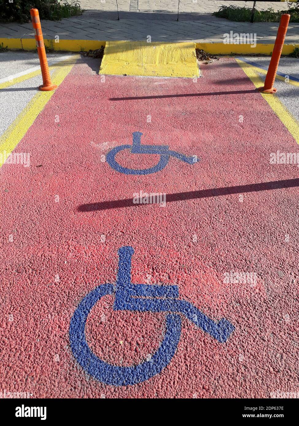 Panneau jaune pour personnes handicapées marquant une place dans un parking, sur fond rouge dans une marina en Grèce Banque D'Images