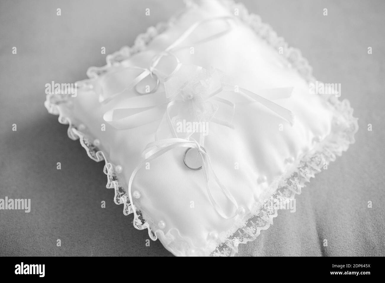 Un gros plan de mariage d'anneaux d'argent sur le blanc coussin en anneau avec rubans Banque D'Images