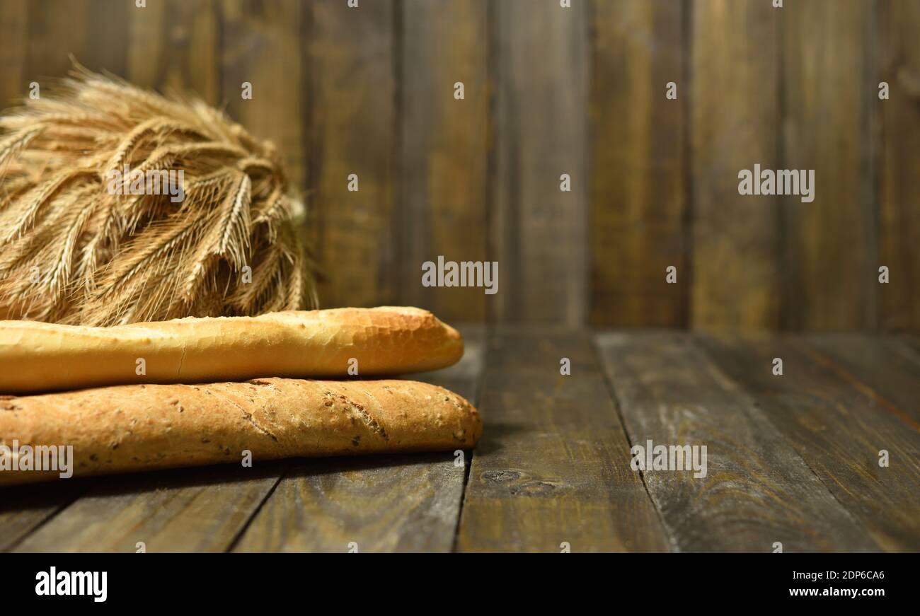 Longue baguette française et oreilles de blé sur fond de bois Banque D'Images