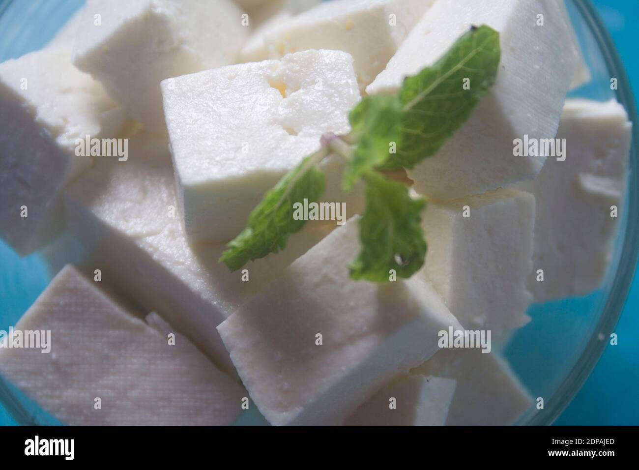 Paneer indien fait maison à base de lait frais et de jus de citron, coupé en dés dans un bol en bois sur fond de pierre grise. Orientation horizontale. Banque D'Images