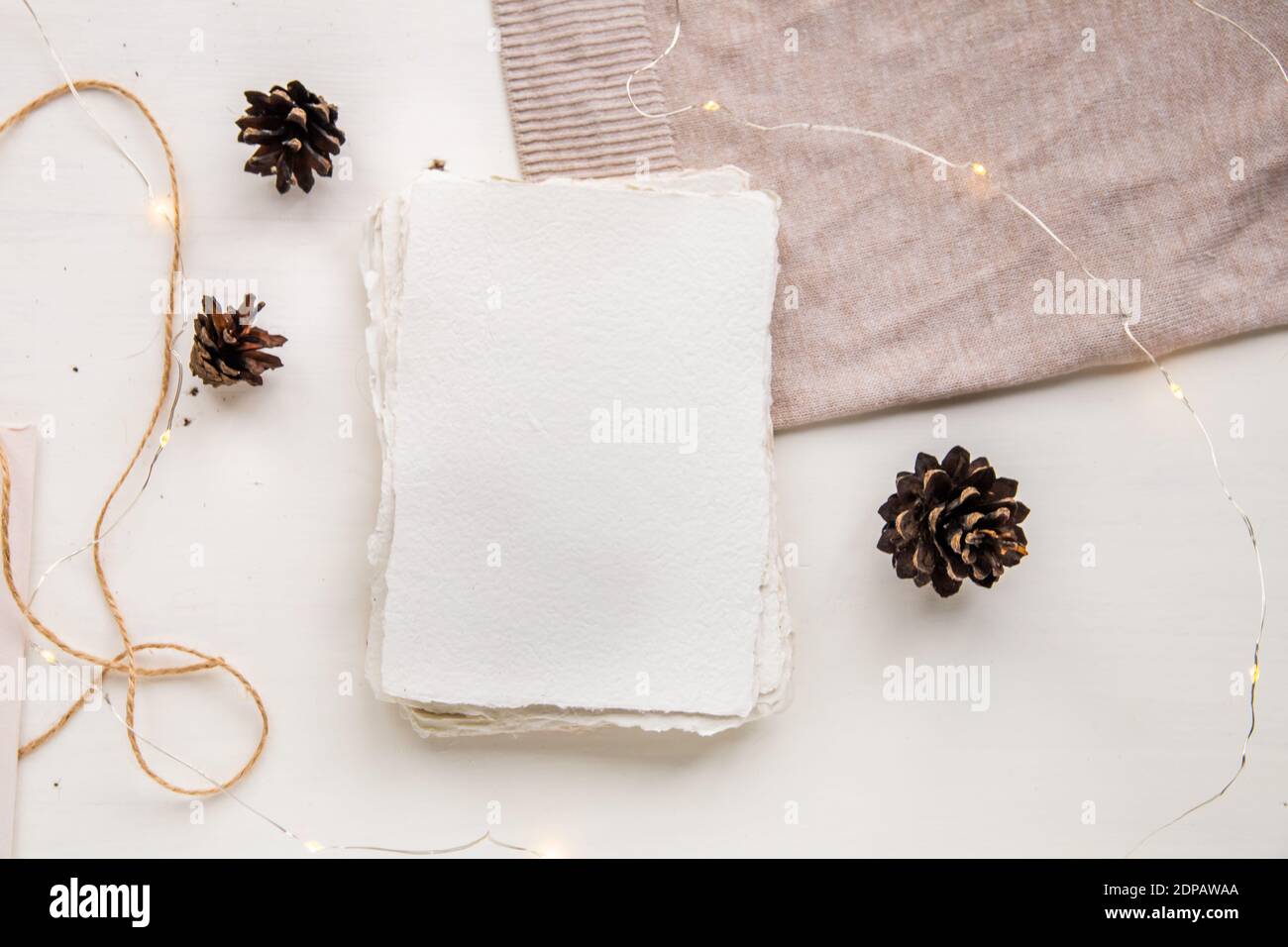 Pose plate style hygge. Liste de souhaits de Noël. Papier fait à la main noué avec des fils artisanaux. Enveloppe maquette de lettre, cônes de pin, fil d'artisanat. Banque D'Images