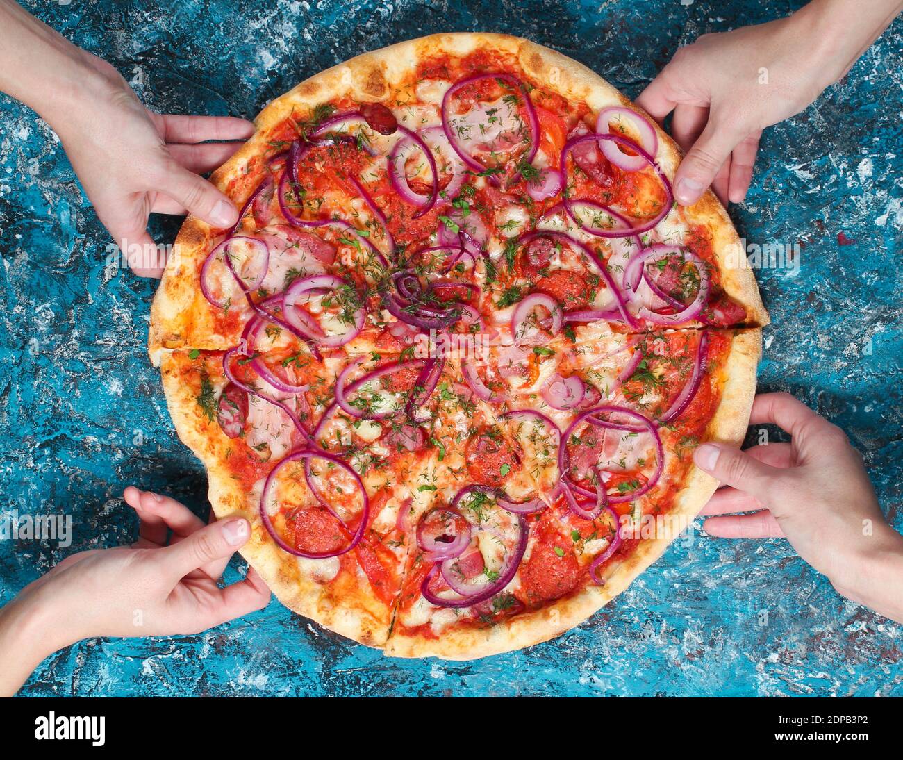 Main prend un morceau de pizza maison sur un béton bleu background.Company amis. En-cas sympa. Vue de dessus Banque D'Images