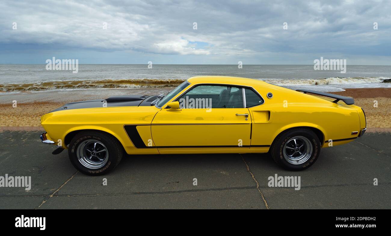 Classic Yellow Ford Mustang garée sur front de mer promenade plage et mer en arrière-plan. Banque D'Images
