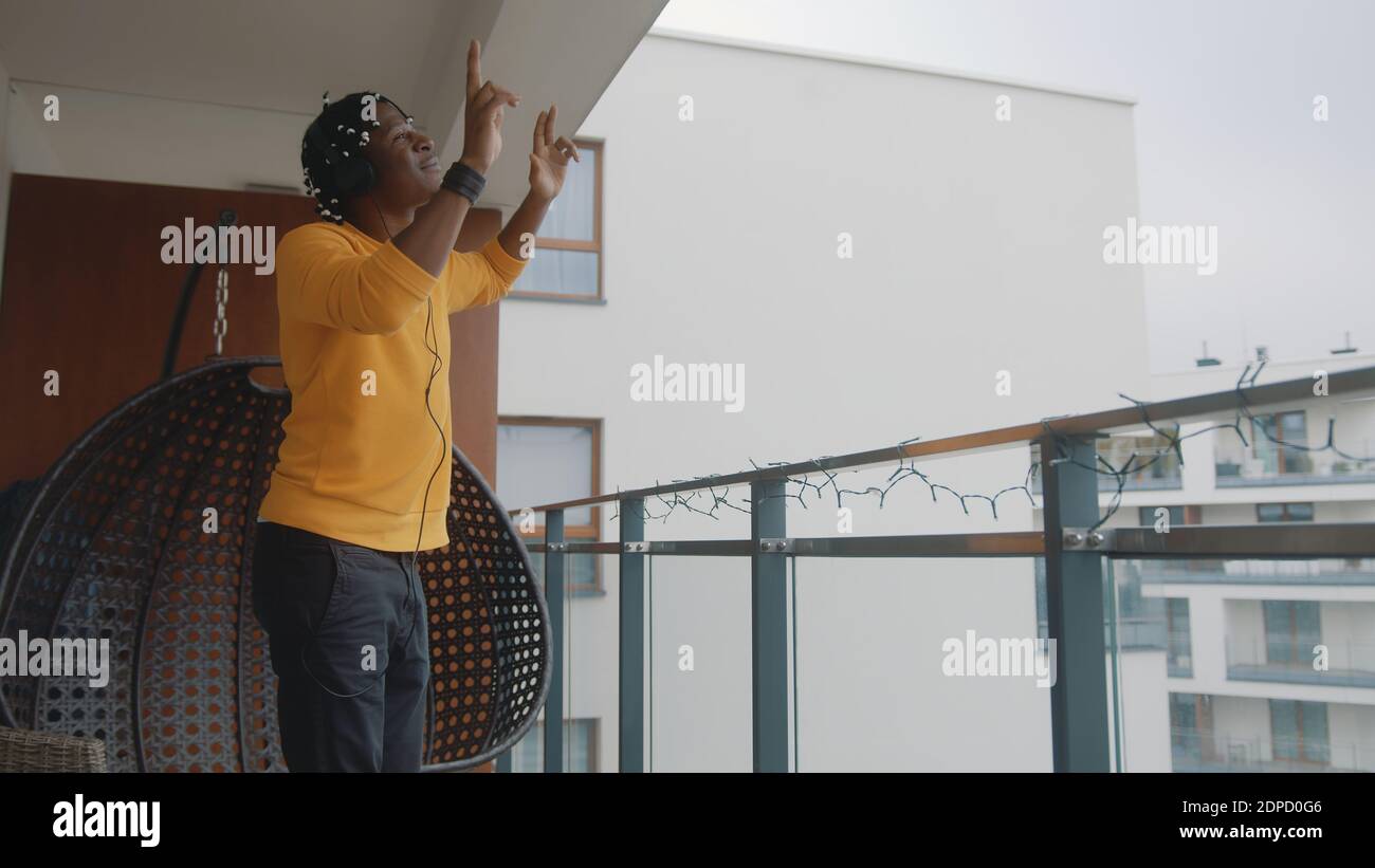 Drôle d'homme noir afro-américain avec des écouteurs dansant sur la terrasse. Photo de haute qualité Banque D'Images