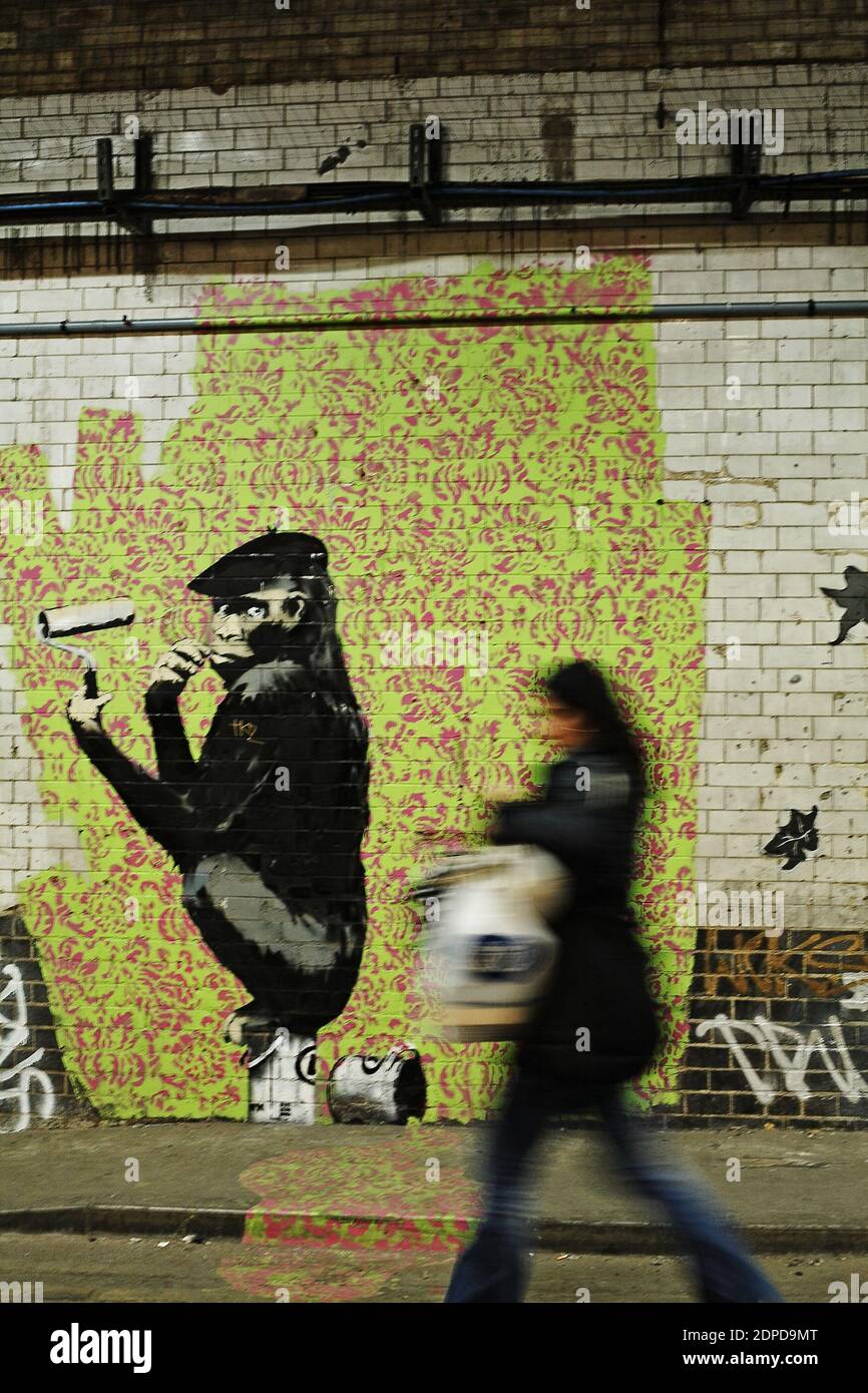 GRANDE-BRETAGNE / Londres / Street Art / UNE femme passe devant une œuvre de graffiti Banksy. Banque D'Images