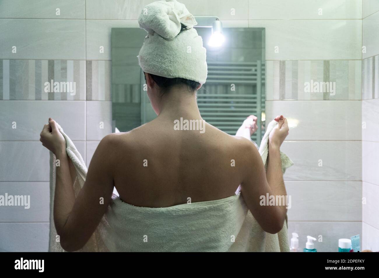 Une jeune femme sèche ses cheveux et son corps avec le serviettes après une  douche et soins du corps devant le miroir de la salle de bains Photo Stock  - Alamy