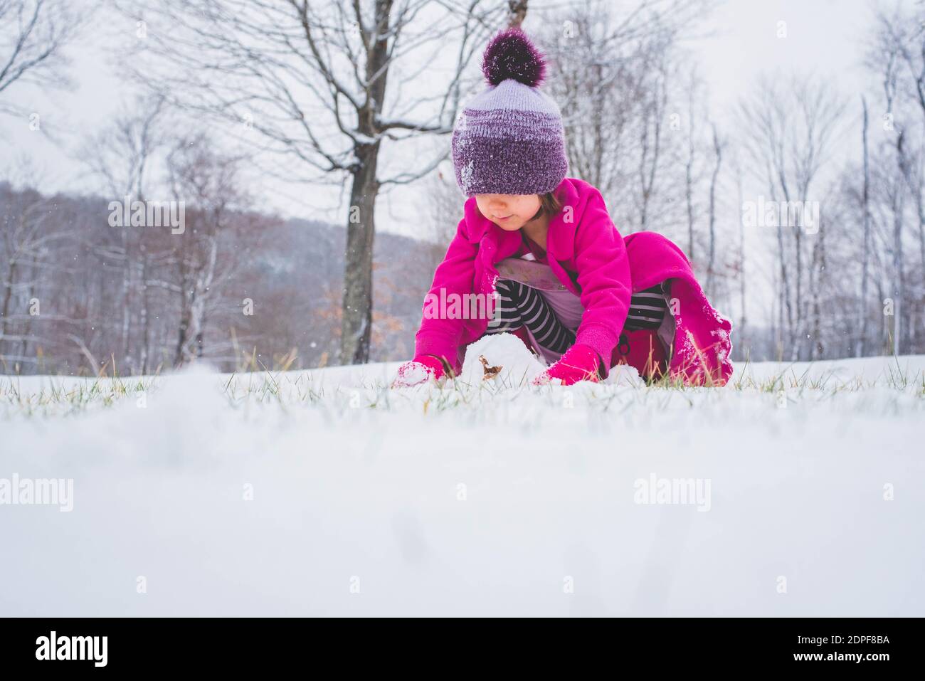Une jeune fille jouant dans la neige et faisant une boule de neige. Banque D'Images