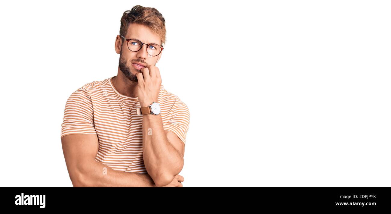 Jeune homme caucasien portant des vêtements et des lunettes décontractés ayant l'air stressé et nerveux avec les mains sur la bouche piquant les ongles. Banque D'Images