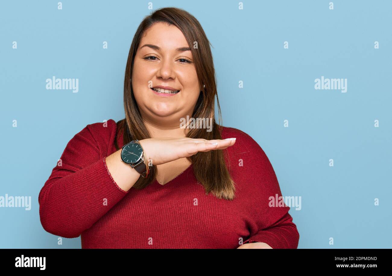 Belle brune plus grande femme portant des vêtements décontractés gesturant avec les mains montrant grand et grand signe de taille, symbole de mesure. Souriant regardant le Banque D'Images