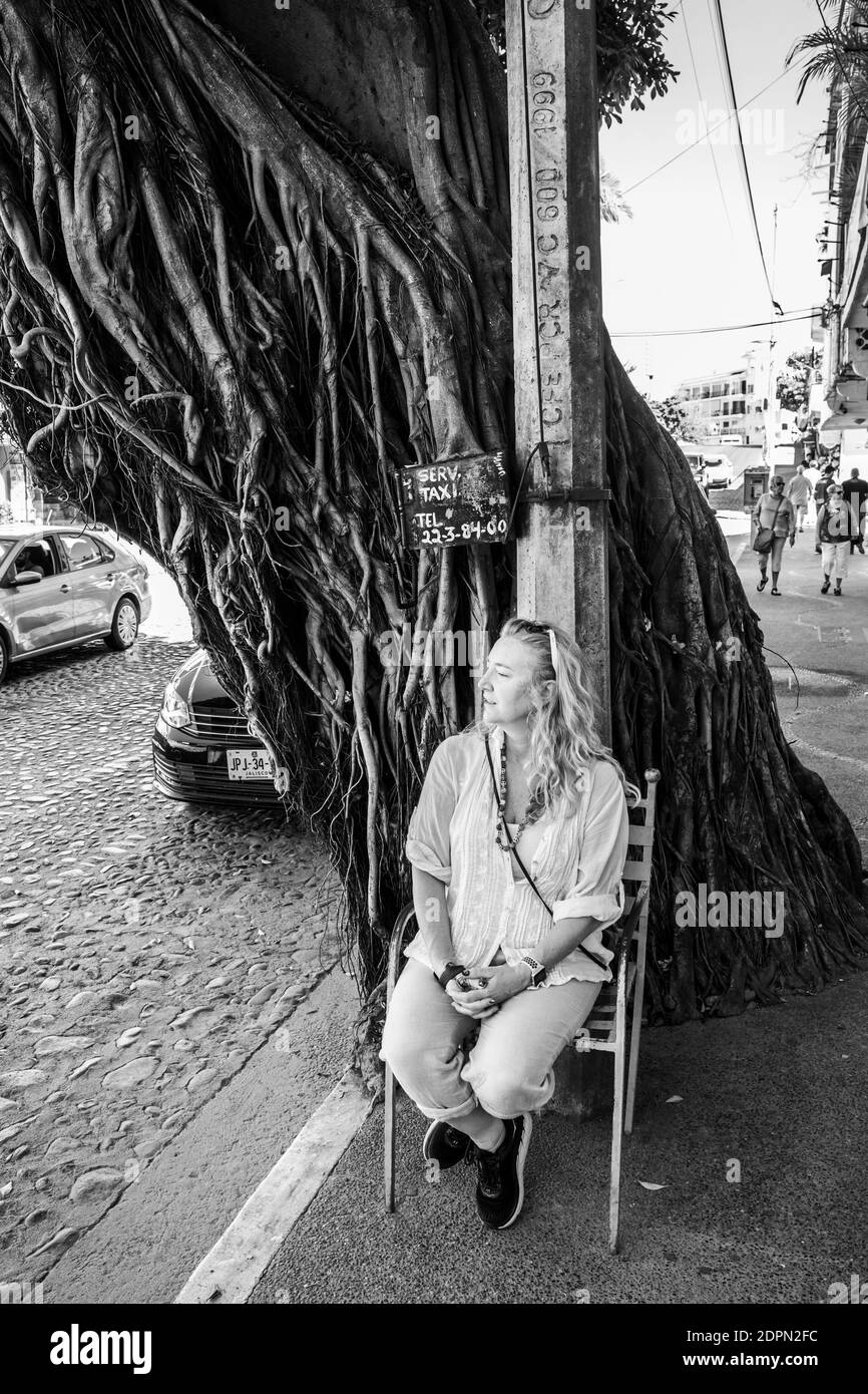 Une femme s'assoit dans une chaise dans la rue à Puerto Vallarta, au Mexique, en attendant un taxi. Banque D'Images