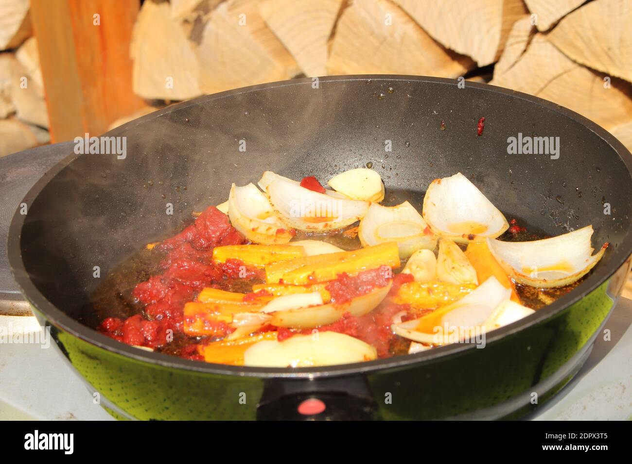 Les oignons et les carottes sont sautés dans une casserole avec de la tomate coller Banque D'Images
